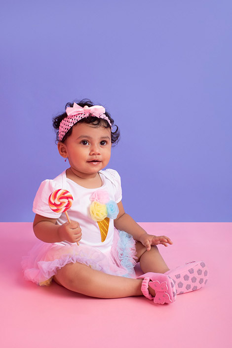 Little girl holding a candy wearing a white top and tutu skirt