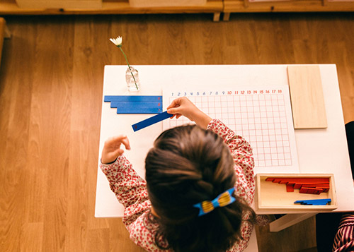 A young girl learning numbers with the help of a chart and fixtures.