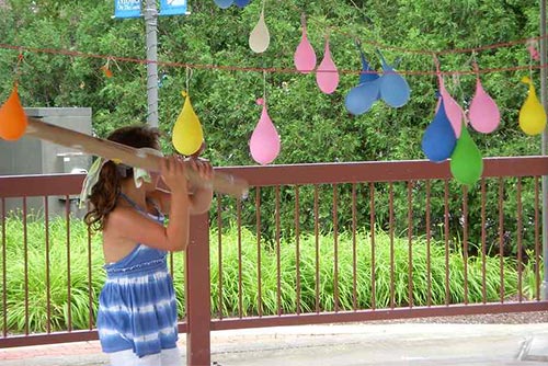 Girl swinging at hanging balloons with a bat