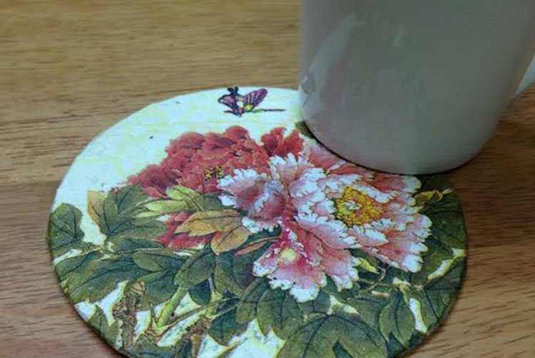 A CD turned into a floral coaster with a mug partially placed on it