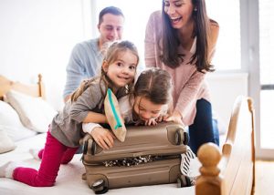 Portrait of a young happy family with two children packing for holiday at home.