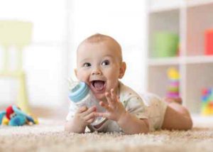 Baby lying down on the floor with a feeding bottle