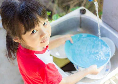 Young girl washing plates and being responsible