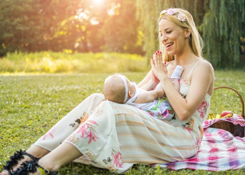 Infant lying in her mother’s lap on green grass