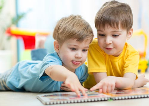 Two young boys reading a picture book