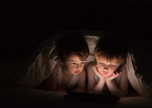 Two brothers reading a story under the sheets in the torchlight!