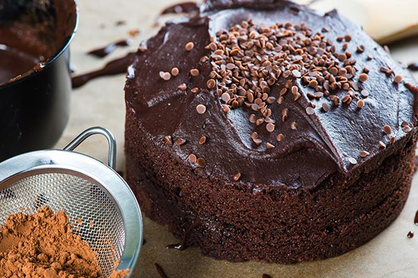 Chocolate cake topped with chocolate sprinkles and cocoa powder on the side