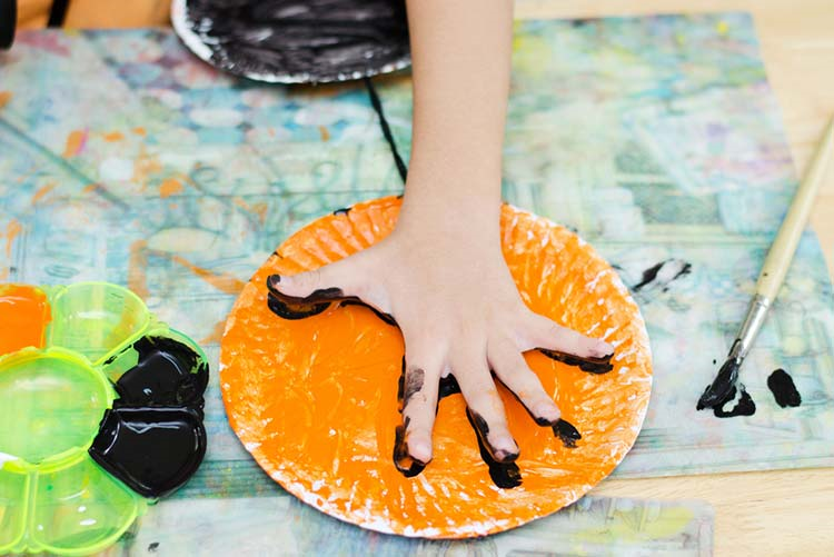 Young child finger painting on a plate!