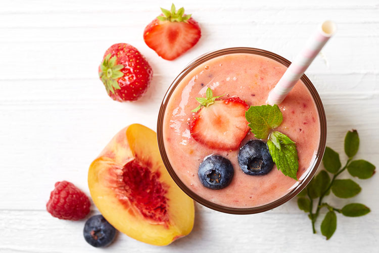 Strawberry smoothie served with chopped peach and berries!