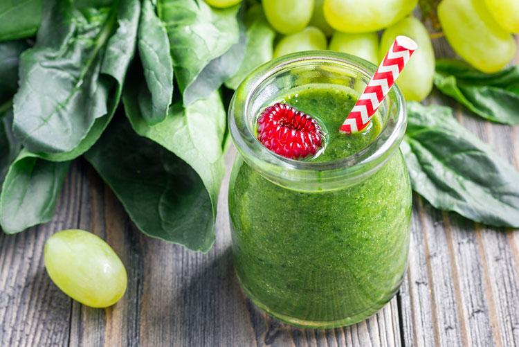 Glass of grape and spinach smoothie served with a straw!