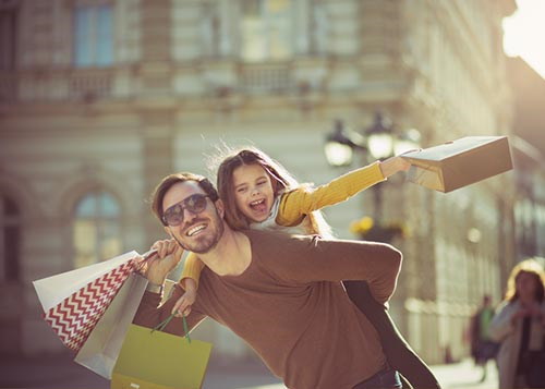 A father and daughter with shopping bags in the city