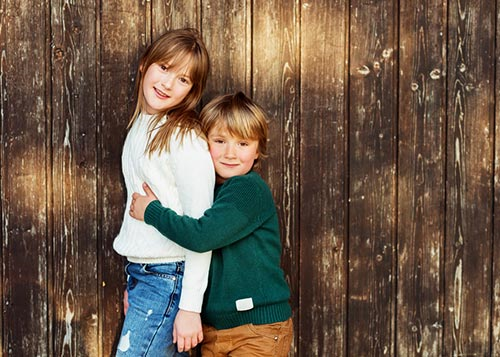 An elder sister with her younger brother holding her affectionately