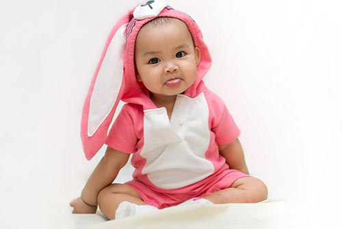 Cute baby in pink dress sticking out his tongue