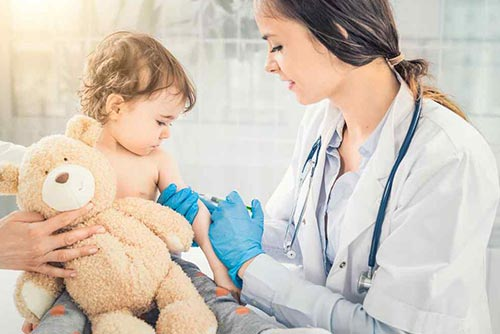 An infant baby being immunised with syringe by lady doctor