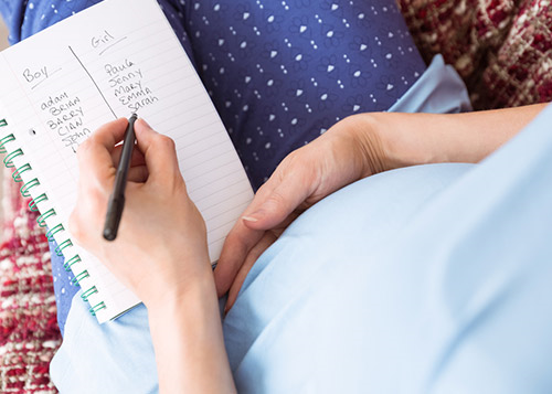Pregnant woman making a list of baby names