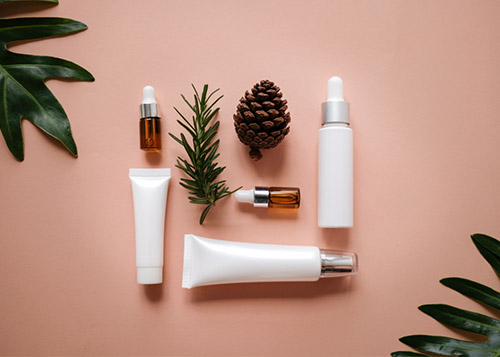 Natural beauty products set against a peach background, surrounded by leaves