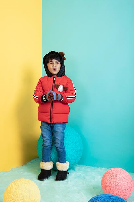 Young boy wearing a winter jacket, woollen hat and winter boots