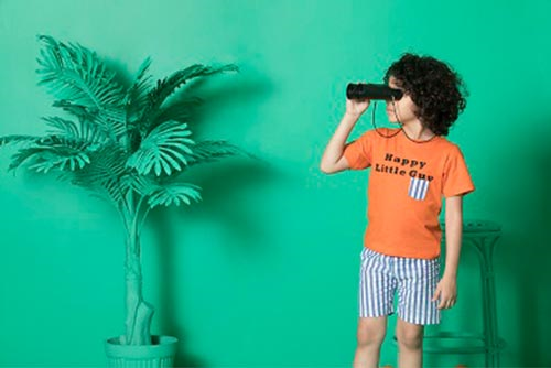 young boy wearing summer casuals holding a pair of binoculars