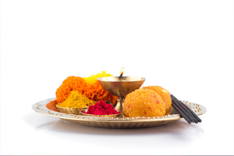 Diwali pooja thali loaded with sweets, flowers, diya, and incense sticks