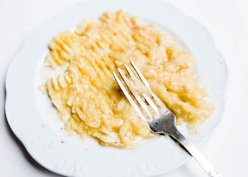 Banana mash baby food served on a white plate with fork