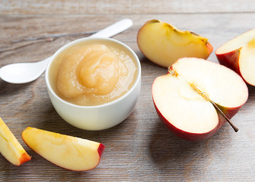 Apple mash served in white bowl with diced apples on the side