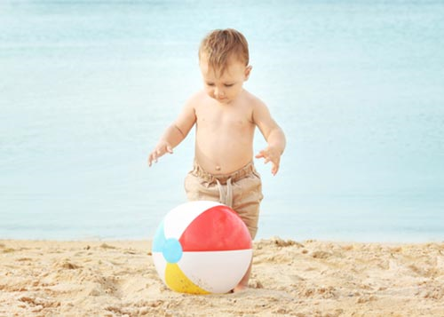 Infant playing ball on a beach!