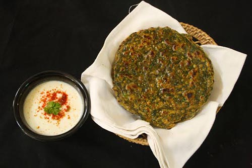 Mashed avocado used as a base to make parathas - a classic Indian dish. Next to a bowl of curd-based dip.