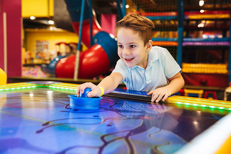 Little boy playing air hockey in a gaming arcade