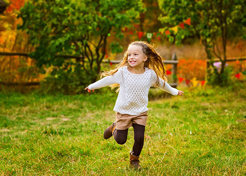 Girl running through a lawn wearing a top and shorts over tights - demonstrating different types of versatile clothing to be packed.