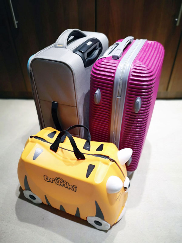 Two adult-sized suitcases next to a cute child’s suitcase. Efficient packing means that every member of the family is responsible for their own suitcase!