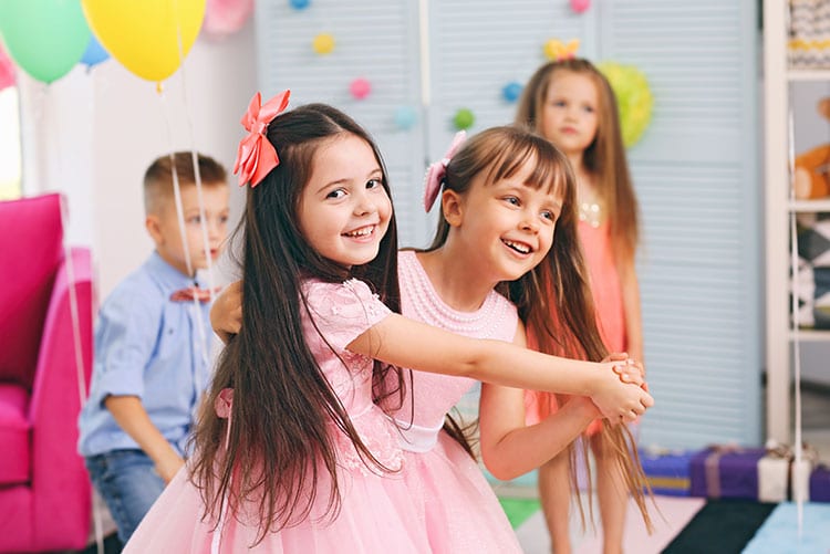 Two girls dancing around at a kid's birthday party.
