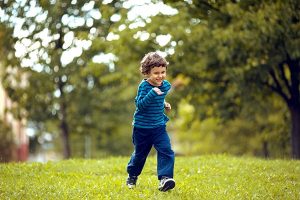A young boy running in a park.