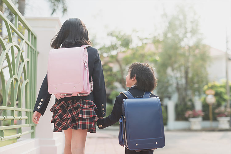 Siblings wearing the same school bag in different colours.