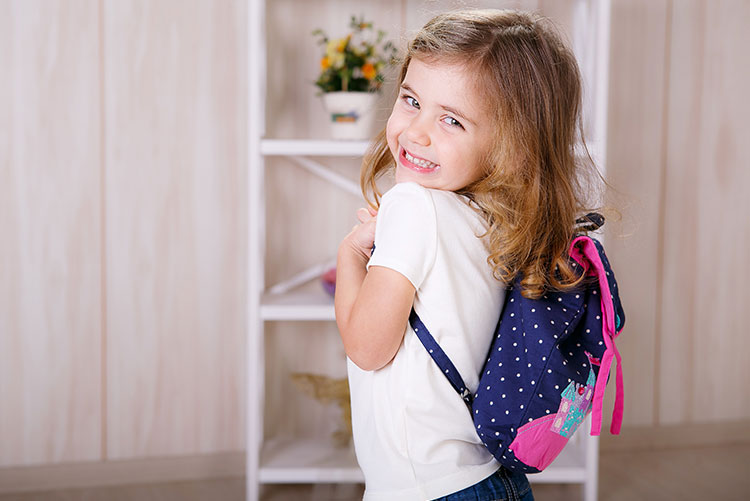 A girl smiling as she shows off her new bag.