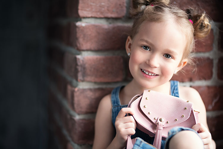 A little girl showing her tiny sling bag.