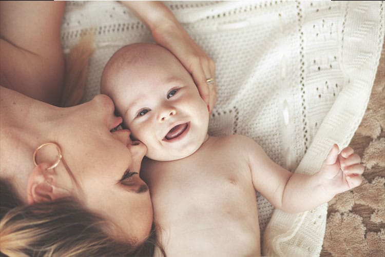 Mother lying down and kissing her baby