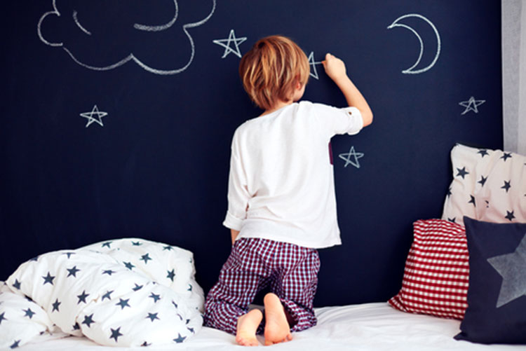 Boy drawing on a chalkboard wall