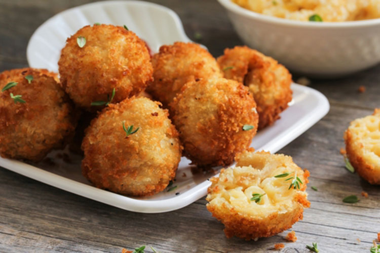 Plate of mac n cheese pakoras and a half-bitten pakora