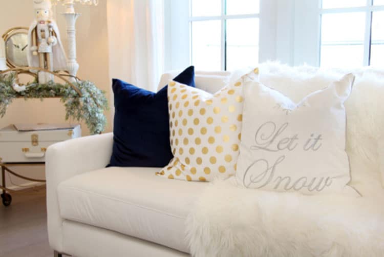 A white couch with festive pillows and a throw rug
