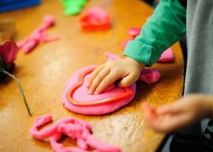 Toddler making hearts out of playdough