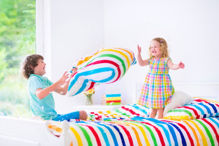 Boy and girl in a pillow fight on a bed