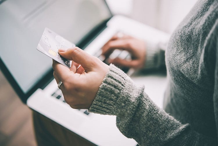 Woman holding a credit card in front of her laptop