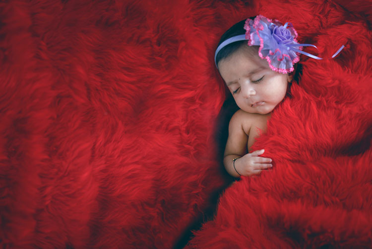 Girl baby sleeping on a red rug
