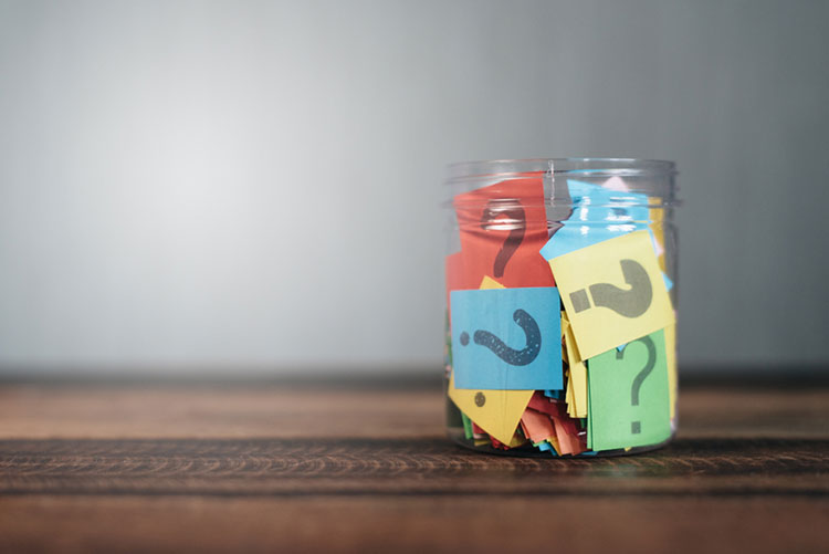 A jar filled with papers with question marks on them