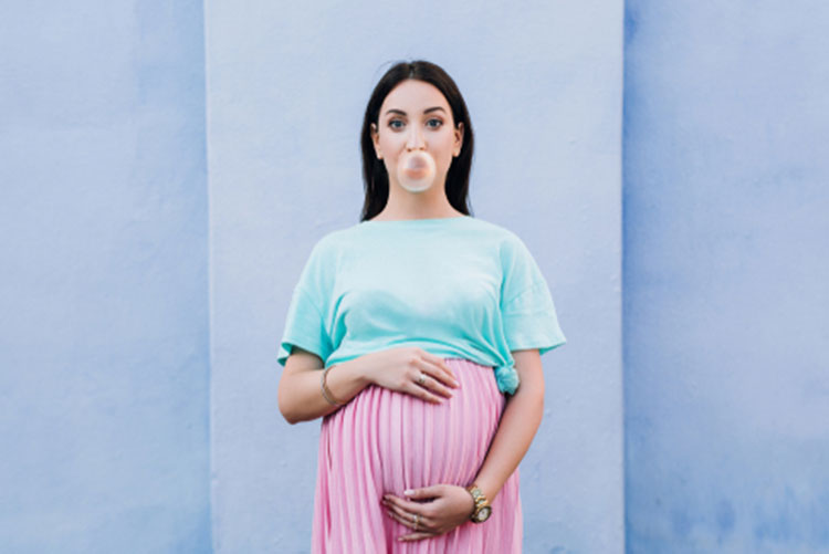 Pregnant woman holding her belly and blowing a bubble