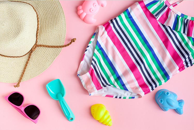 Beachwear and beach toys arranged on a wooden plank.