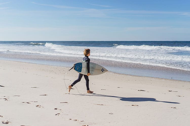 A young running towards the water with a surfboard.