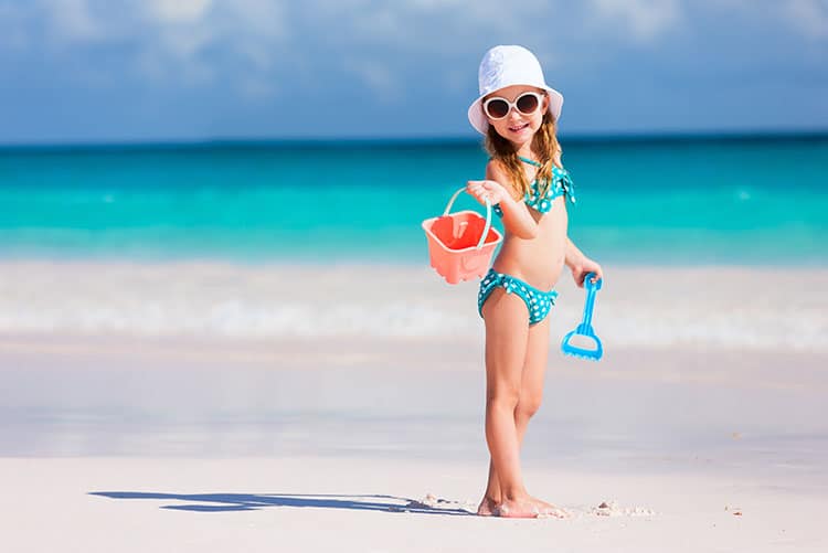 A young girl, sporting a baby bikini, all set to build sandcastles.