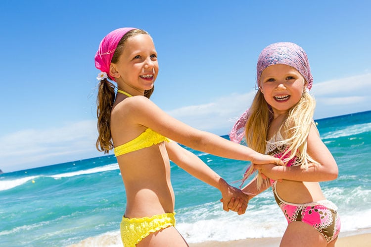 Two girls holding hands on the beach.