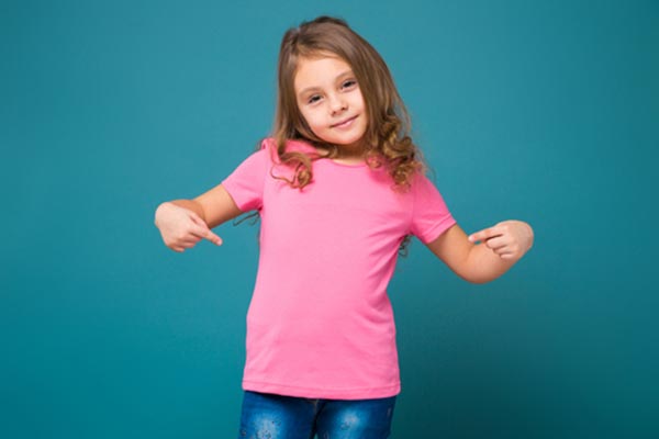 Little girl wearing a pink tee-shirt and pointing at her tee-shirt